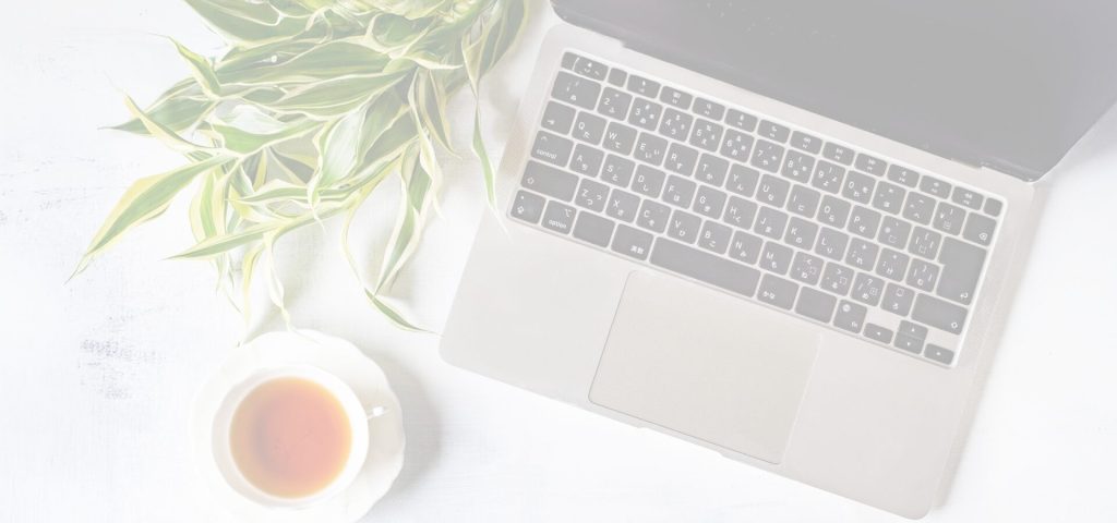Overhead view of laptop sitting next to a plant and a tea cup